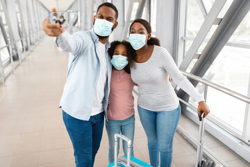 Black family in face masks taking selfie in airport
