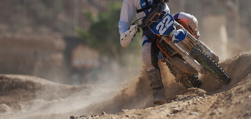 Racer boy on motorcycle participates in motocross race, active extreme sport, flying debris from a...