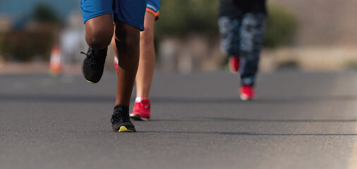 Fototapeta na wymiar Running children, young athletes run in a kids run race,running on city road detail on legs,running in the light of morning