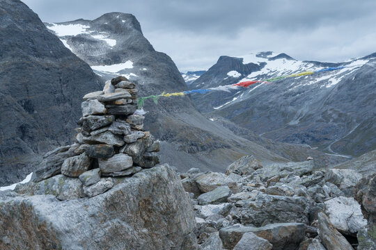 Stone mound with dramatic mountain scenery in the back on the hiking trail to Trollvegen in Norway. Cloudy day in Norwegian nature. Hiking Scandinavia around Trollstigen road.