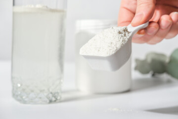 hand holding scoop of fish collagen. collagen peptides in container or jar. powder for mixing drink. Healthcare supplement concept. collagen for skin and joints.