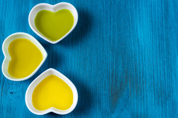 Blue wooden background with three sauce boats with different types of olive oil, copy space.