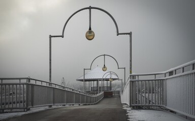 Bremen, Germany. First hoarfrost at Weserwehr weir next to swb Stadtwerke power plant beneath Weser river in foggy ice cold Hastedt. Chemical industry and moody bridges - obrazy, fototapety, plakaty