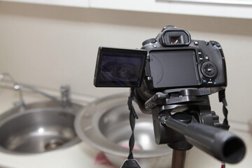 Professional DSLR photo camera on kitchen sink background, home interior work video recording