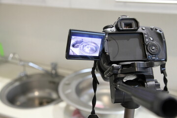 Professional DSLR photo camera on tripod on kitchen sink background, blogger home interior development photography