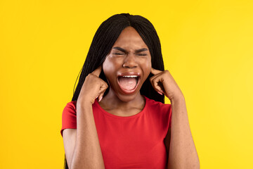 African American Woman Shouting Plugging Ears With Fingers, Yellow Background