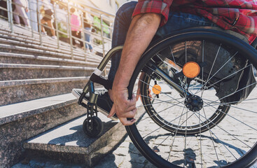 Fototapeta premium Young man with a physical disability who uses wheelchair in front of the stairs