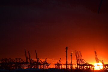 Dramatic sunset behind industrial port horizon