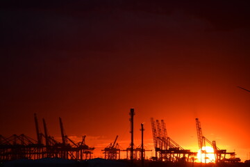 Dramatic sunset behind industrial port horizon