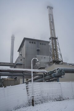 Bremen, Germany. First hoarfrost at Weserwehr weir next to swb Stadtwerke power plant beneath Weser river in foggy ice cold Hastedt. Chemical industry and moody bridges