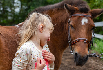little girl laugh with pony horse in equestrian club