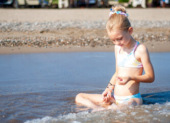 Little girl playing on the beach by the sea