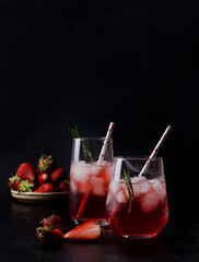 Cold cocktail with strawberries and ice on a black background. Summer drinks in a dark way