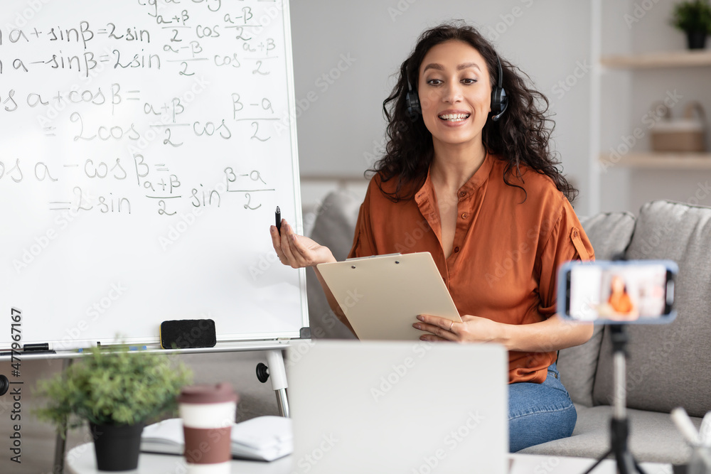 Wall mural Female teacher in headset explaining trigonometric functions to students online