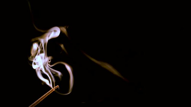 An incense stick burns and smokes.