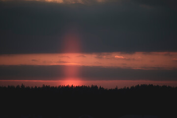 Obraz premium Rare optical phenomenon view in winter. Bright orange light pillar with ice crystals in cold air, Lithuania. Selective focus on the details, blurred background.