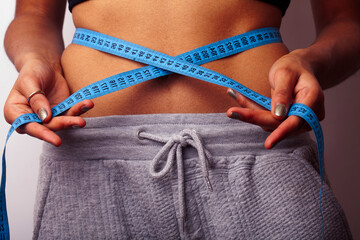 woman measuring waist with tape on knot, african tan isolated