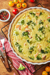 Homemade quiche with red fish, salmon, broccoli and cheese on wooden background