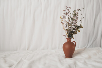 Beautiful Wildflowers flower arrangement in stylish Clay vase white natural cotton fabrics background.
