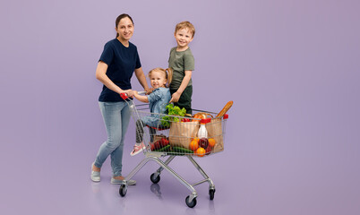 Mom smiles while shopping, a girl and a boy are sitting in a grocery cart. Isolated concept image of the shopping with cjpe space.