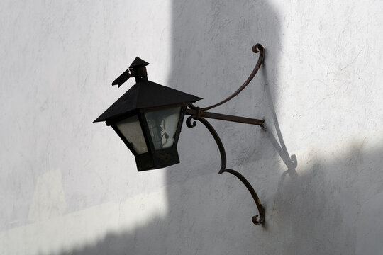 Old black vintage outdoor lamp on the street wall.