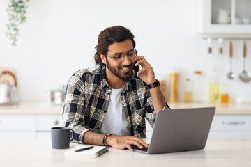 Busy arab man freelancer talking on phone and using laptop