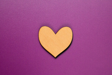 Natural wooden heart flat lay on purple background.
