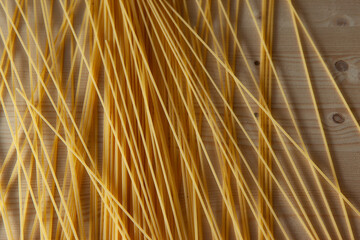 Yellow Spaghetti scattered on the table. Italian food concept. Spaghetti artistic background for publication, design, poster, calendar, post, screensaver, wallpaper, postcard, banner, cover, website