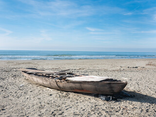 hull of a shipwrecked small sailboat on the beach - 477972527