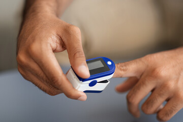 Male hands using pulse oximeter, closeup photo