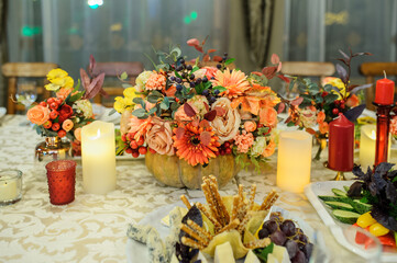 Autumn flower table decorations in a pumpkin, with candles. .