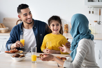 Family Meal. Happy Muslim Parents And Little Daughter Eating In Kitchen Together