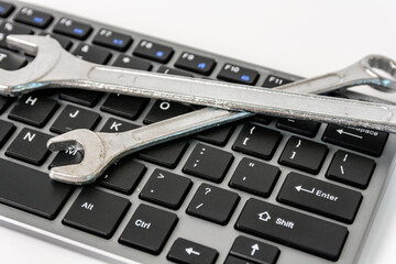 Computer keyboard with wrenchs for computer technical support maintenance concept.