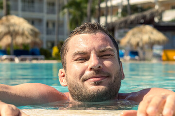 A smiling man relaxes in the hotel's swimming pool.