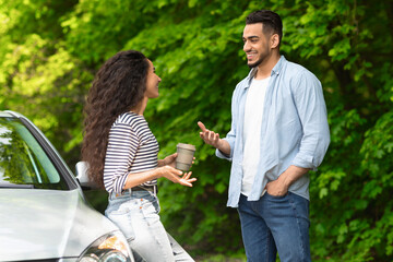 Joyful multiracial couple having coffee break while car trip