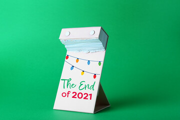 Tear-off calendar at the end of the year 2021 on color background
