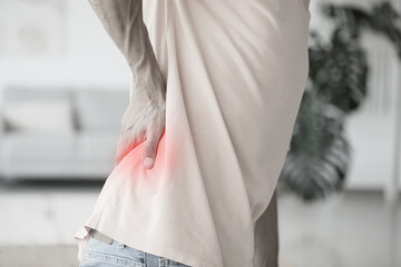 Young man suffering from back pain at home