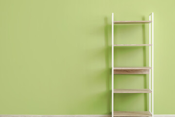 Empty wooden shelving unit near green wall