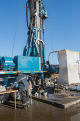 A worker operates a drilling rig close-up at a construction site. Deep hole drilling. Extraction of minerals oil and gas. Working process.