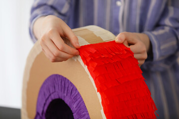 Woman making Mexican pinata in shape of rainbow at home, closeup