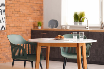 Glasses of water and cookies on dining table in kitchen