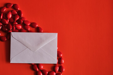 A envelope and Red beads on a red background with space for text or logo.
