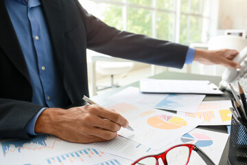 Businessman working with diagrams at desk in office, closeup