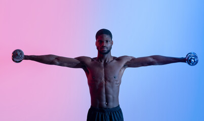 Strong young black man with naked torso lifting dumbbells in neon light, panorama