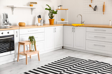 Interior of modern kitchen with white counters and wooden step stool