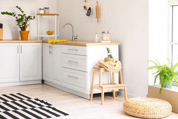 Interior of light kitchen with white counters and wooden step stool