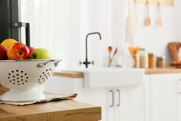 Colander with fruits on wooden table top in kitchen