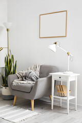 Interior of light living room with lamps, table and armchair