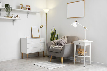 Interior of light living room with lamps, armchair and commode
