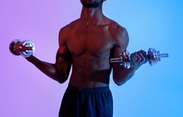 Fototapeta na wymiar Unrecognizable black guy with sexy body training with dumbbells, pumping up muscles in neon light, closeup